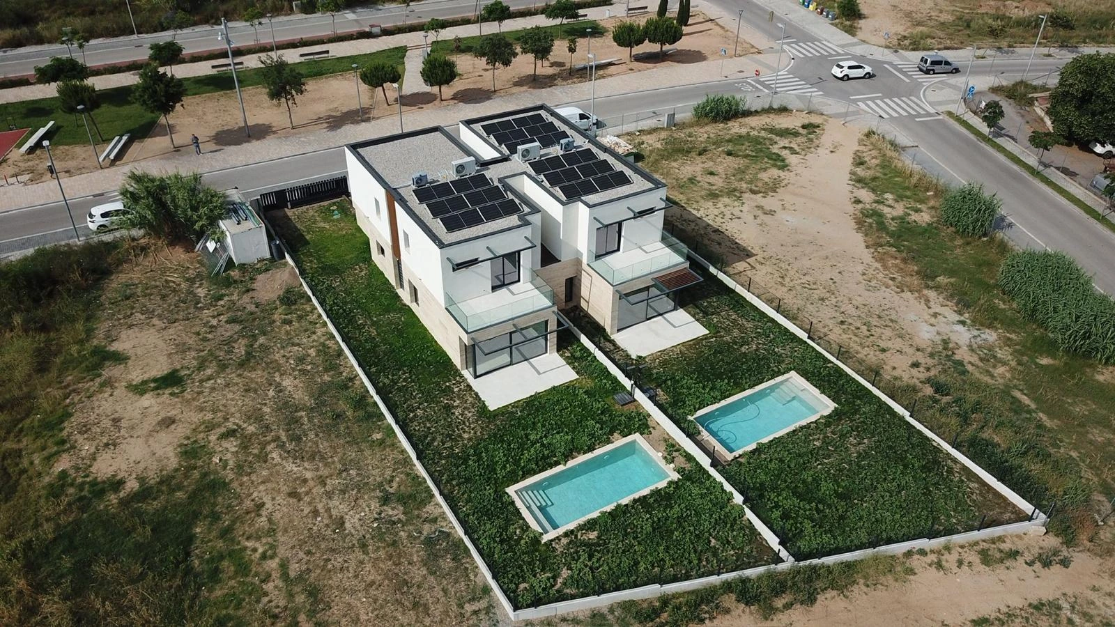 Vista aérea de dos viviendas unifamiliares con jardín y piscina